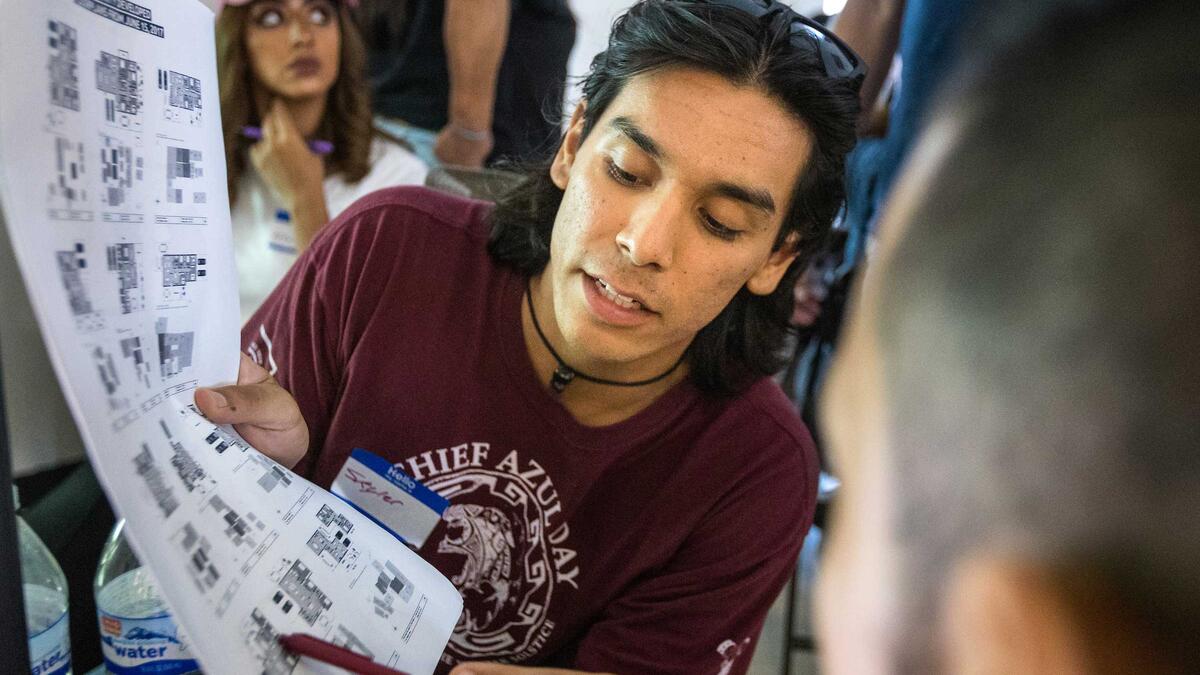 Person demonstrating something on a set of blueprints